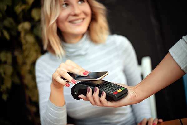 Frau hält Handy an Kartenlesegerät